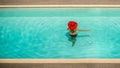 Beautiful girl in a swimsuit and a red hat in a blue water pool Royalty Free Stock Photo