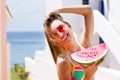 Beautiful girl in a swimsuit and sunglasses holds a piece of watermelon at the resort background hotel. Happy summer woman Royalty Free Stock Photo