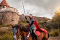 A beautiful girl with a sword in a medieval fantasy suit. A woman in a chain mail, crown, on a horse in combat ammunition. A girl