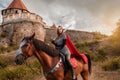 A beautiful girl with a sword in a medieval fantasy suit. A woman in a chain mail, crown, on a horse in combat ammunition. A girl