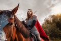 A beautiful girl with a sword in a medieval fantasy suit. A woman in a chain mail, crown, on a horse in combat ammunition. A girl Royalty Free Stock Photo