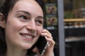 Cute young brunette girl talking on a cell phone. She smiles and looks away. She is without makeup, natural pleasant beauty. No Royalty Free Stock Photo