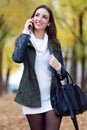 Beautiful girl talking on phone in autumn.