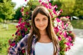 Beautiful girl teenager 13-16 years on the background of a flower bed. Happy smiles. In the summer in city after school Royalty Free Stock Photo