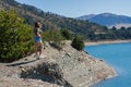 Beautiful girl in a teeshirt ans denim shorts standing at the mountain lakeshore Royalty Free Stock Photo