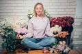 Cute lovely young woman florist sitting in lotus position in flower shop. Royalty Free Stock Photo