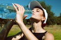 Beautiful girl with a tennis racket against a background of nature drinking water Royalty Free Stock Photo