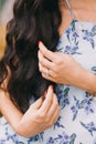 Beautiful girl are touching by her hand`s long, black and curly hair. Close-up. Royalty Free Stock Photo