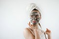 beautiful girl in towel applying black caly mask on face isolated on white gray