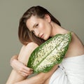 A beautiful girl with towel on her head holds a green leaf in her hands. Cleanliness and care