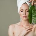 Beautiful girl with towel on her head holds a green leaf in her hands. Cleanliness and care