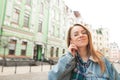 Beautiful girl traveler in glasses and denim jacket listening to music in headphones with closed eyes on the background of the Royalty Free Stock Photo