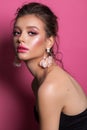 A beautiful girl with trendy professional pink makeup, pink accessories and pink background. Side view.