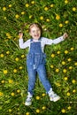 A beautiful girl with two tails is lying on her back in a field of dandelions. the view from the top. summer child Royalty Free Stock Photo