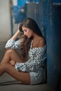 Beautiful girl with unbuttoned shirt posing, old wall with peeling blue paint on background. Pretty brunette sitting on the Royalty Free Stock Photo