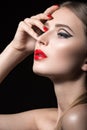 Beautiful girl with unusual black arrows on eyes and red lips and nails. Beauty face. Royalty Free Stock Photo