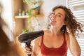 Happy smiling woman using hair dryer in bathroom Royalty Free Stock Photo