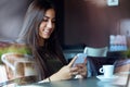 Beautiful girl using her mobile phone in cafe. Royalty Free Stock Photo