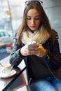 Beautiful girl using her mobile phone in cafe. Royalty Free Stock Photo