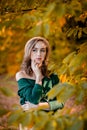 Beautiful girl walking outdoors in autumn. Smiling girl collects yellow leaves in autumn. Young woman enjoying autumn weather