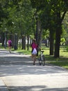 a beautiful girl walks along a path in the park and rolls a bicycle next to her