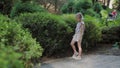 Beautiful girl walks by the green bush.