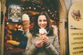 A beautiful girl in a warm jacket eats trdelnik or Trdlo with cream in her hands, in the winter in the Czech Republic, Prague at t