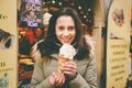 A beautiful girl in a warm jacket eats trdelnik or Trdlo with cream in her hands, in the winter in the Czech Republic, Prague at t