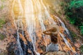 Beautiful girl on a waterfall in Thailand. A girl in a straw hat rests in a shady jungle Royalty Free Stock Photo