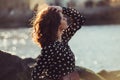 Beautiful girl wearing black polka dots dress enjoy summer sun on ocean beach at sunset time. Royalty Free Stock Photo