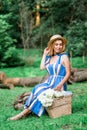 Beautiful girl wearing blue dress and hat collect flowers in basket in the wood. Royalty Free Stock Photo