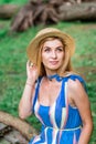 Beautiful girl wearing blue dress and hat collect flowers in basket in the wood. Royalty Free Stock Photo