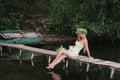 Beautiful girl wearing a crown sitting on a wooden bridge with a cat Royalty Free Stock Photo