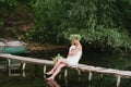 Beautiful girl wearing a crown sitting on a wooden bridge with a cat