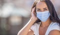 Beautiful girl wearing disposable facemask, looking into the camera during the coronavirus outbreak