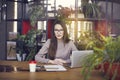 Beautiful girl wearing eye glasses in coworking studio. Using laptop and smartphone at the wooden table. Concept of young people w