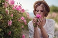 Beautiful girl wearing hat with book sitting on grass in rose gaden Royalty Free Stock Photo