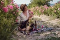 Beautiful girl wearing hat with book sitting on grass in rose gaden Royalty Free Stock Photo