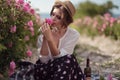 Beautiful girl wearing hat with book sitting on grass in rose gaden Royalty Free Stock Photo