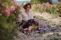 Beautiful girl wearing hat with book sitting on grass in rose gaden Royalty Free Stock Photo