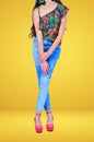 Beautiful girl wearing jeans. With red shoes and a bright color shirt. Yellow Background in a Photographic Studio.