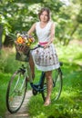 Beautiful girl wearing a nice white dress having fun in park with bicycle. Healthy outdoor lifestyle concept. Vintage scenery Royalty Free Stock Photo