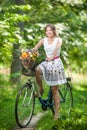 Beautiful girl wearing a nice white dress having fun in park with bicycle. Healthy outdoor lifestyle concept. Vintage scenery Royalty Free Stock Photo