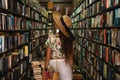 Beautiful girl wearing stylish outfit looking for interesting book in the vintage bookstore