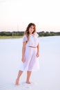 Beautiful girl wearing white dress walking barefoot on sand. Royalty Free Stock Photo