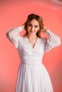 Beautiful girl wears a white summer dress on a pink background