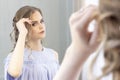 Beautiful girl with a wedding hairstyle looks at herself in the mirror, portrait of a young girl. beautiful make-up. Royalty Free Stock Photo