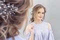 Beautiful girl with a wedding hairstyle looks at herself in the mirror, portrait of a young girl. beautiful make-up. Royalty Free Stock Photo