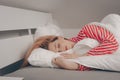 A beautiful girl on a white bed in red striped pajamas is sleeping. Healthy sleep. Woman with closed eyes and long sutra hair on Royalty Free Stock Photo