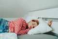 A beautiful girl on a white bed in red striped pajamas is sleeping. Healthy sleep. Woman with closed eyes and long sutra hair on Royalty Free Stock Photo